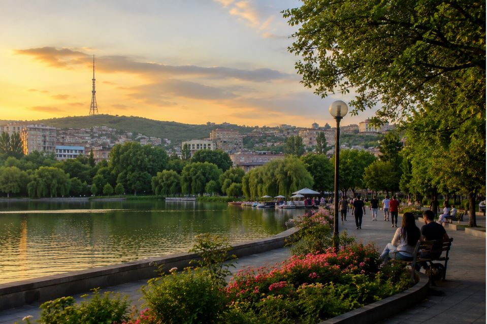 Peaceful evening park in Yerevan with lake, walking people and sunset over the hills